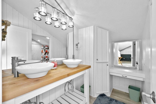 bathroom featuring wood-type flooring, lofted ceiling, vanity, and a shower with curtain