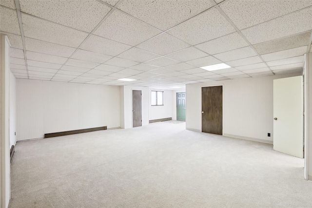 basement featuring light colored carpet, a drop ceiling, and baseboard heating