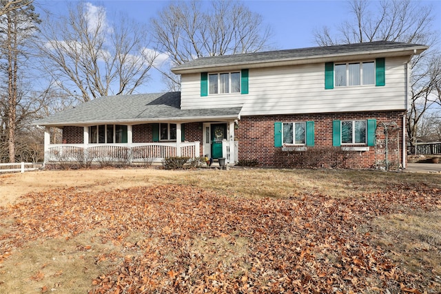 view of front of property featuring covered porch, roof with shingles, and brick siding