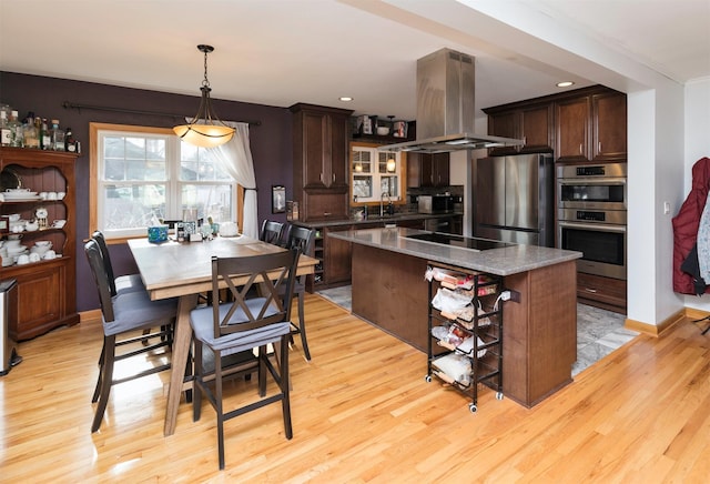 kitchen featuring dark brown cabinets, island exhaust hood, appliances with stainless steel finishes, and a kitchen island