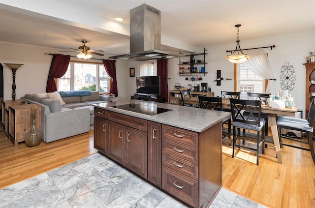 kitchen featuring decorative light fixtures, black electric cooktop, a kitchen island, island exhaust hood, and light stone countertops