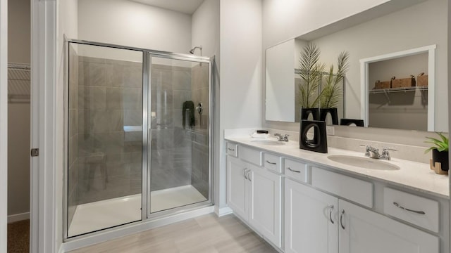 bathroom with an enclosed shower, vanity, and wood-type flooring