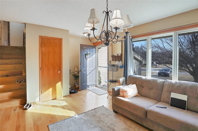 living room featuring a notable chandelier, light hardwood / wood-style floors, and a textured ceiling