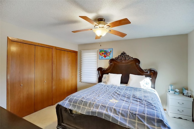 carpeted bedroom featuring multiple closets, ceiling fan, and a textured ceiling