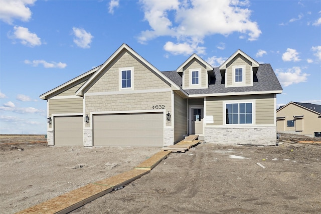 view of front facade featuring stone siding, driveway, and a shingled roof