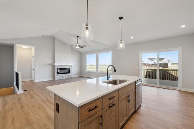 kitchen with light wood-style flooring, a fireplace, a sink, stainless steel dishwasher, and decorative light fixtures