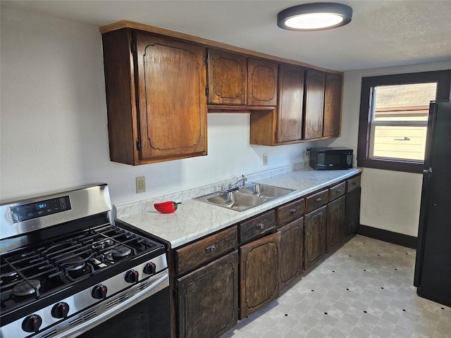 kitchen featuring dark brown cabinetry, sink, and black appliances