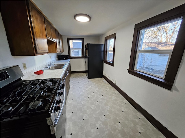 kitchen featuring black refrigerator, sink, and stainless steel range with gas stovetop