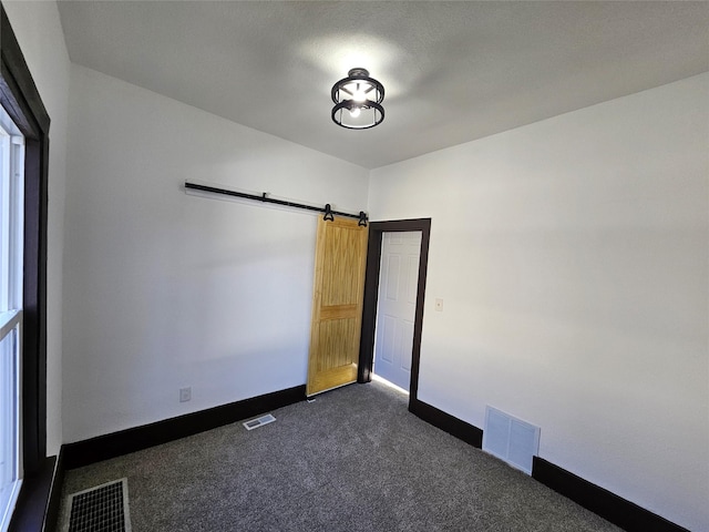 carpeted empty room featuring a barn door