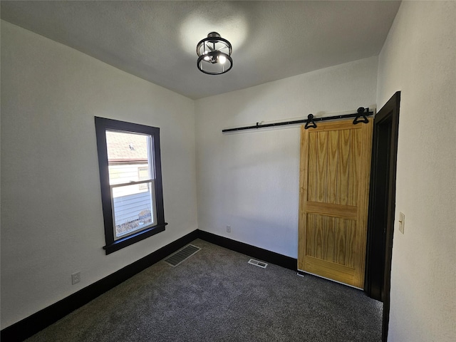 carpeted empty room with a barn door