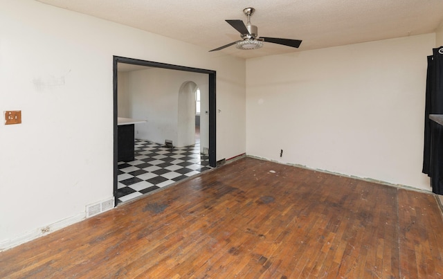 unfurnished room featuring dark wood-type flooring, ceiling fan, and a textured ceiling