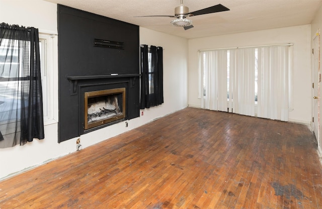 unfurnished living room featuring hardwood / wood-style flooring, ceiling fan, a textured ceiling, and a fireplace