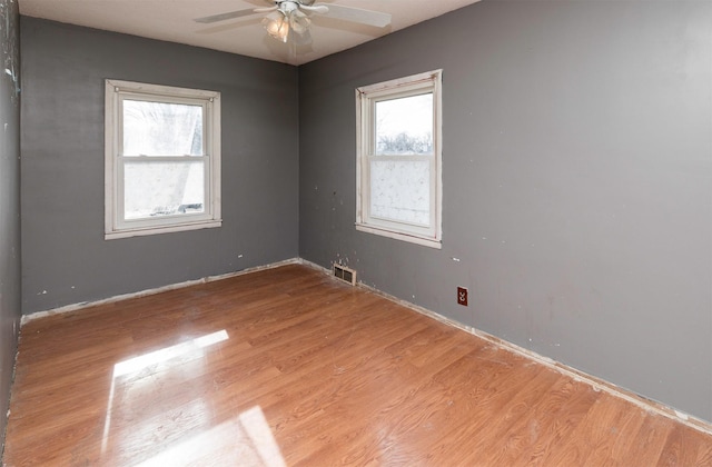 empty room with ceiling fan, plenty of natural light, and light hardwood / wood-style floors