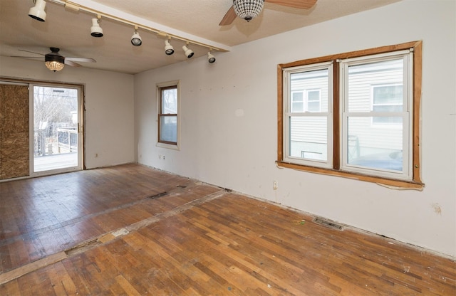 empty room featuring wood-type flooring, a wealth of natural light, and ceiling fan