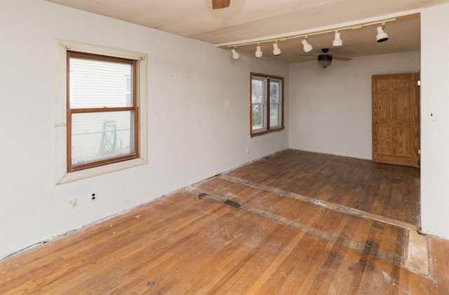 spare room featuring ceiling fan, track lighting, and hardwood / wood-style floors