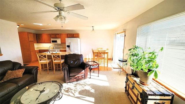 living room featuring light colored carpet, a textured ceiling, and ceiling fan