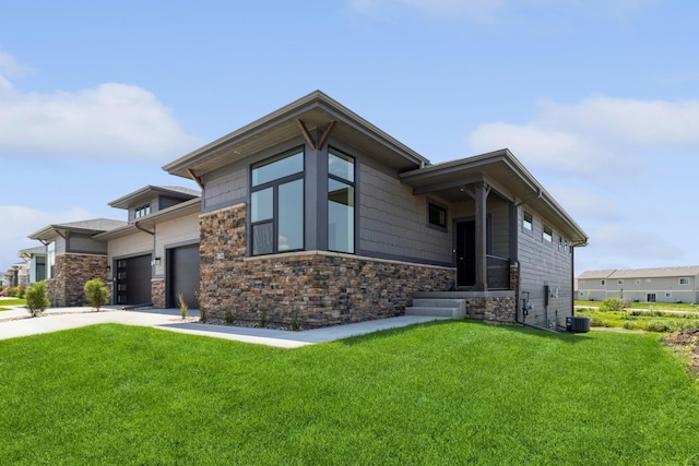 view of front of property with a garage, central AC, and a front lawn