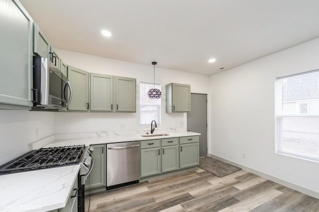 kitchen with sink, decorative light fixtures, stainless steel appliances, and light stone countertops