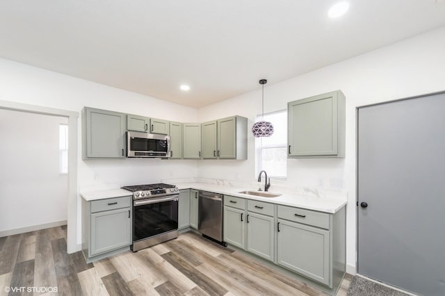 kitchen featuring pendant lighting, sink, light wood-type flooring, and appliances with stainless steel finishes