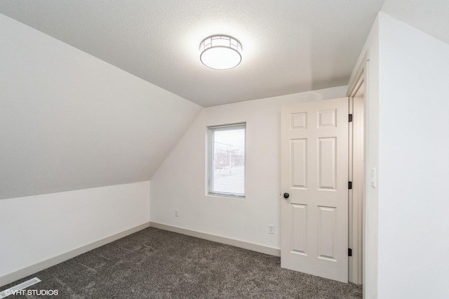 bonus room with lofted ceiling, a textured ceiling, and dark carpet