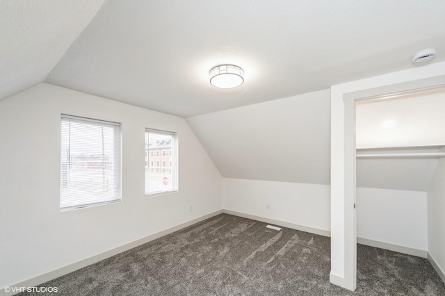 bonus room featuring vaulted ceiling and dark carpet