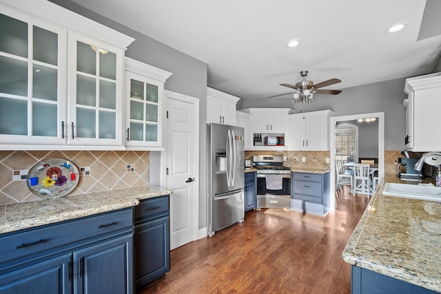 kitchen with blue cabinets, appliances with stainless steel finishes, sink, and white cabinets