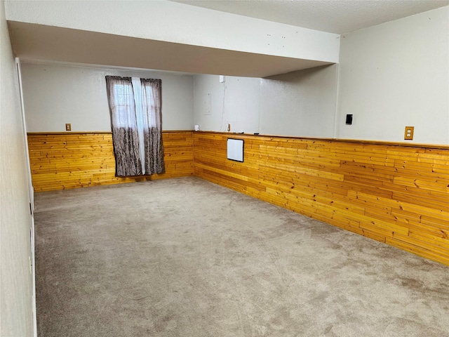 unfurnished room with carpet, wood walls, and a textured ceiling