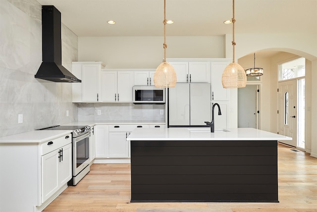 kitchen featuring sink, wall chimney range hood, stainless steel electric range, hanging light fixtures, and white refrigerator