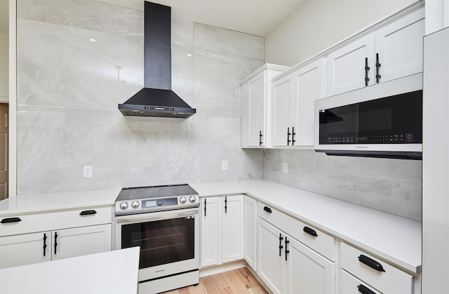 kitchen with range hood, white cabinets, backsplash, and stainless steel range with electric stovetop