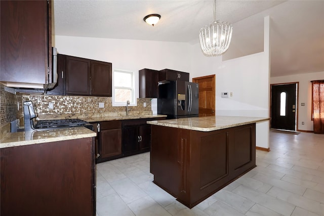 kitchen featuring a kitchen island, hanging light fixtures, range, light stone countertops, and black refrigerator with ice dispenser