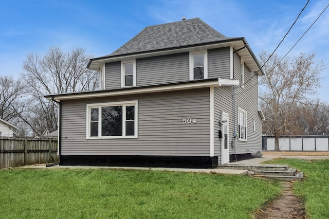 rear view of property featuring a yard and fence