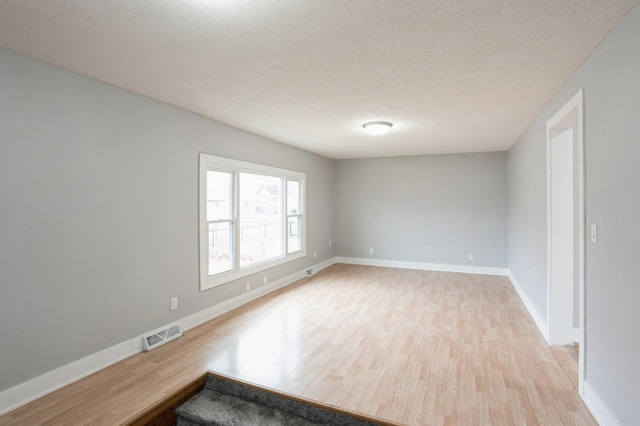 504 E Jackson Ave, Des Moines, IA 50315 - unfurnished room featuring a textured ceiling, visible vents, light wood-style flooring, and baseboards