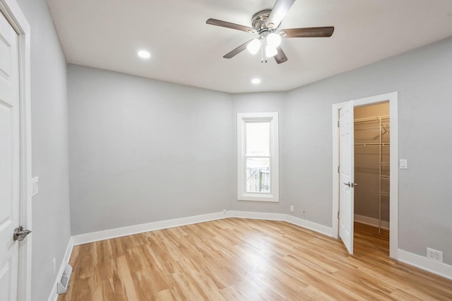 unfurnished bedroom featuring light wood-type flooring, baseboards, and a spacious closet