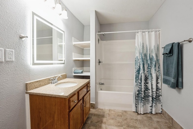 504 E Jackson Ave, Des Moines, IA 50315 - full bath featuring vanity, shower / bathtub combination with curtain, a textured wall, and stone finish floors