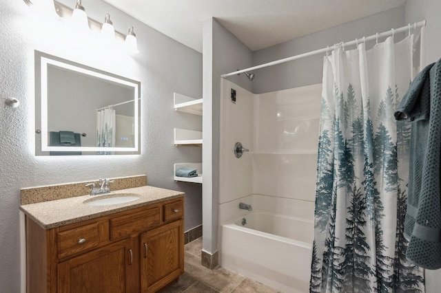 full bathroom with shower / tub combo with curtain, vanity, and a textured wall