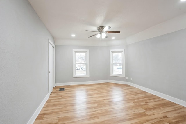 empty room featuring baseboards, visible vents, a ceiling fan, and light wood-style floors