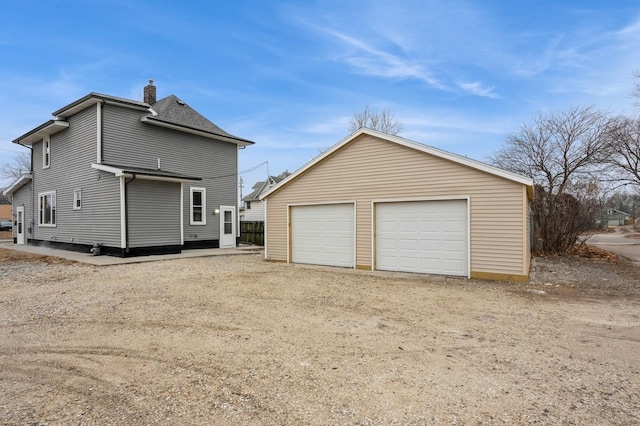 exterior space with a garage, an outdoor structure, and a chimney