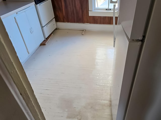 interior details featuring white gas range oven, light wood-type flooring, and white cabinets