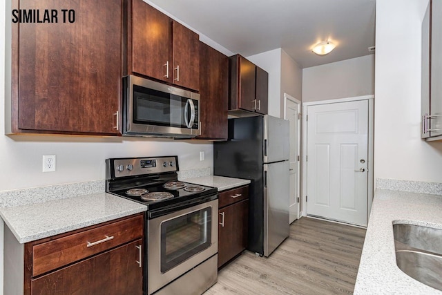 kitchen featuring dark brown cabinets, appliances with stainless steel finishes, and light hardwood / wood-style flooring