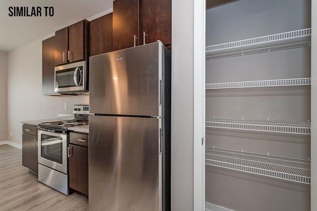 kitchen featuring stainless steel appliances, light hardwood / wood-style floors, and dark brown cabinets