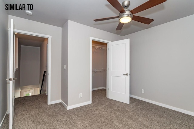 unfurnished bedroom with ceiling fan, a closet, a spacious closet, and carpet