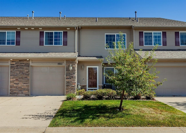 townhome / multi-family property featuring a garage and a front lawn