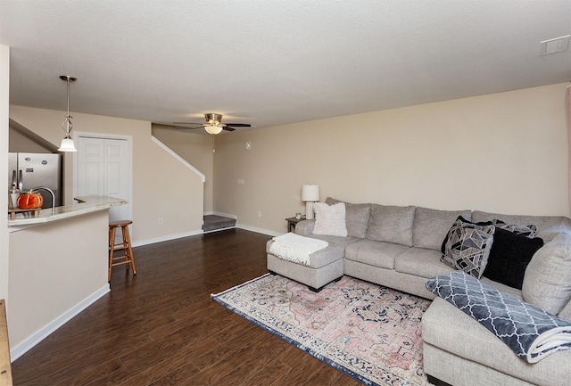 living room featuring ceiling fan, dark hardwood / wood-style flooring, and a textured ceiling