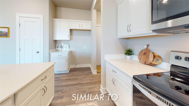 kitchen featuring stainless steel appliances, light wood-style floors, light countertops, white cabinets, and baseboards