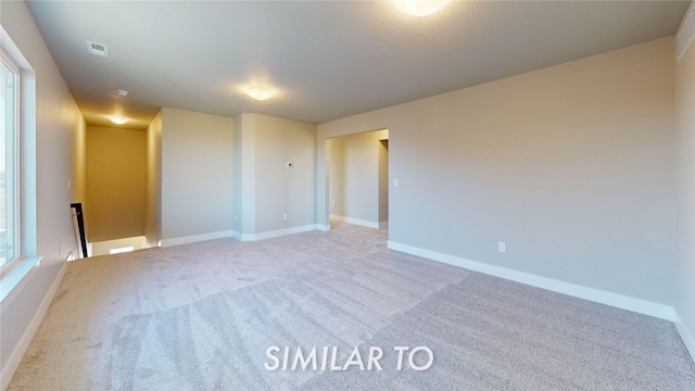 carpeted empty room featuring visible vents and baseboards