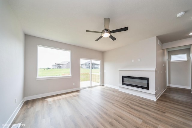 1461 S 91st St, West Des Moines, IA 50266 - unfurnished living room with wood finished floors, a glass covered fireplace, plenty of natural light, and a ceiling fan