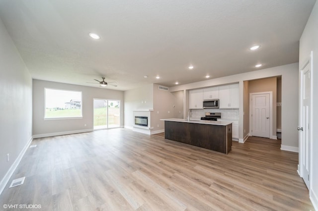1461 S 91st St, West Des Moines, IA 50266 - kitchen with stainless steel appliances, open floor plan, a ceiling fan, a kitchen island with sink, and white cabinets