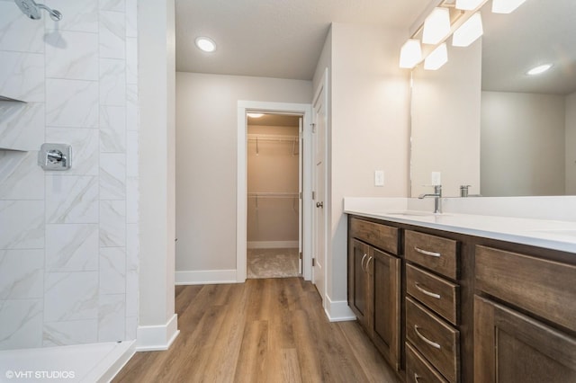 1461 S 91st St, West Des Moines, IA 50266 - bathroom with double vanity, wood finished floors, a tile shower, and a walk in closet