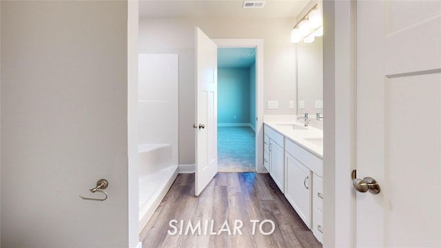 full bath featuring a sink, double vanity, baseboards, wood finished floors, and visible vents