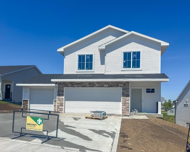 5616 Leyden Ave, Des Moines, IA 50317 - view of front of property featuring driveway, a garage, stone siding, and roof with shingles